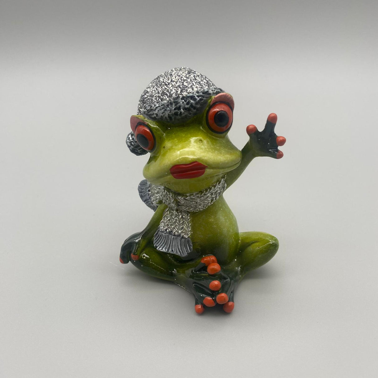 Deko Winterfrosch hellgrün aus Kunststein | Dekofigur Winter Frosch Frau mit Schal sitzend mit Hand nach oben von Wimpelberg